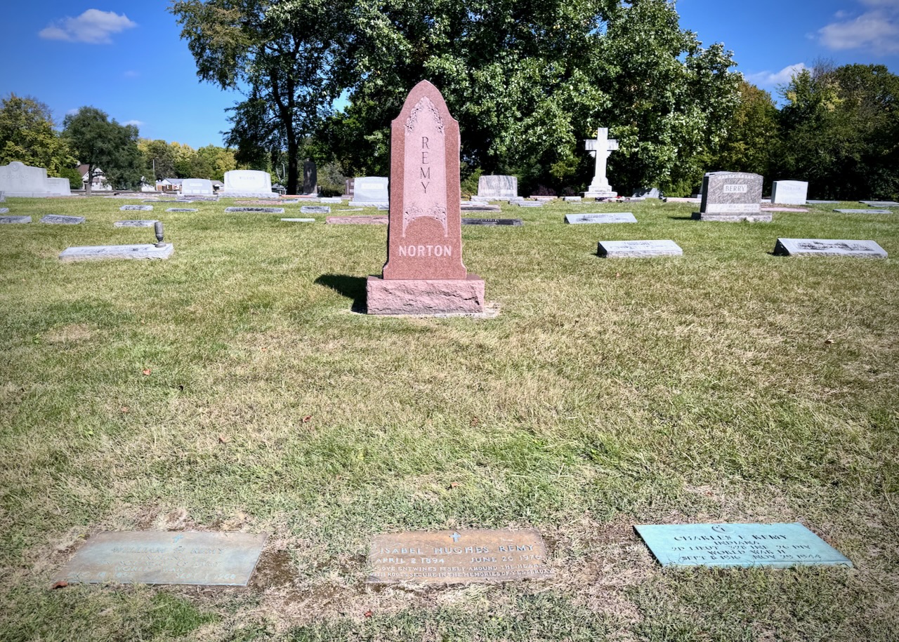 Picture of cemetery with one upright headstone with the name REMY going down the middle. Under that it says NORTON. There are three footstones for William H. Remy (husband), Isabel Hughes Remy (wife), and Charles E. Remy (son).